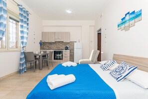 Ein Hotelzimmer mit Bett, Schreibtisch, Stuhl, einer Küchenzeile und einem Badezimmer.