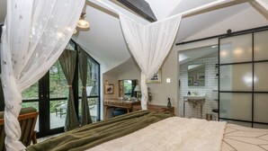 A bedroom with a large bed, a vanity with a mirror, and a view of a balcony. - Windyridge (Rhyl)