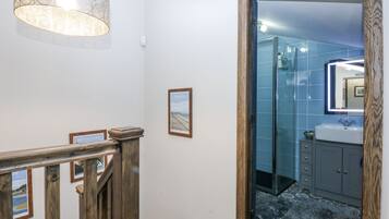 A bathroom with a glass shower enclosure, a sink, and a mirror.