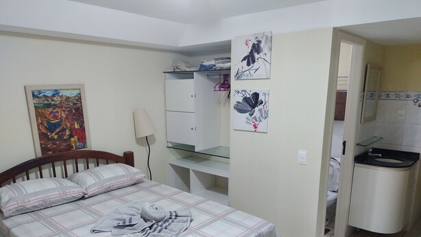 Una camera da letto con un letto, una scrivania, uno specchio e un bagno parzialmente visibile attraverso una porta aperta.