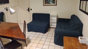 Un soggiorno con divano, tavolo, lampada, televisore e un quadro appeso al muro.