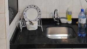Una piccola cucina con un lavello, un frullatore e un espositore per piatti.