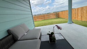 A covered patio with a grey sofa and a small potted plant.