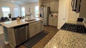 A modern kitchen with granite countertops, stainless steel appliances, and a central island.