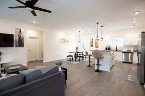 Una cocina moderna con armarios blancos, un refrigerador de acero inoxidable y una zona de comedor con mesa y sillas.