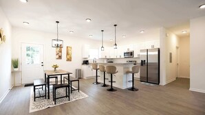 Een moderne keuken met witte kasten, een centraal eiland, barstoelen en een eettafel met stoelen.
