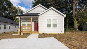 A single-story house with a front porch, a red door, and a small front yard. - 4 Min to Downtown | 10 to Elon | Car Rental Avail. (Burlington)