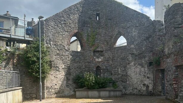 An outdoor courtyard with stone walls, a paved ground, and wooden benches. - The Courtyard Retreat (Sligo)