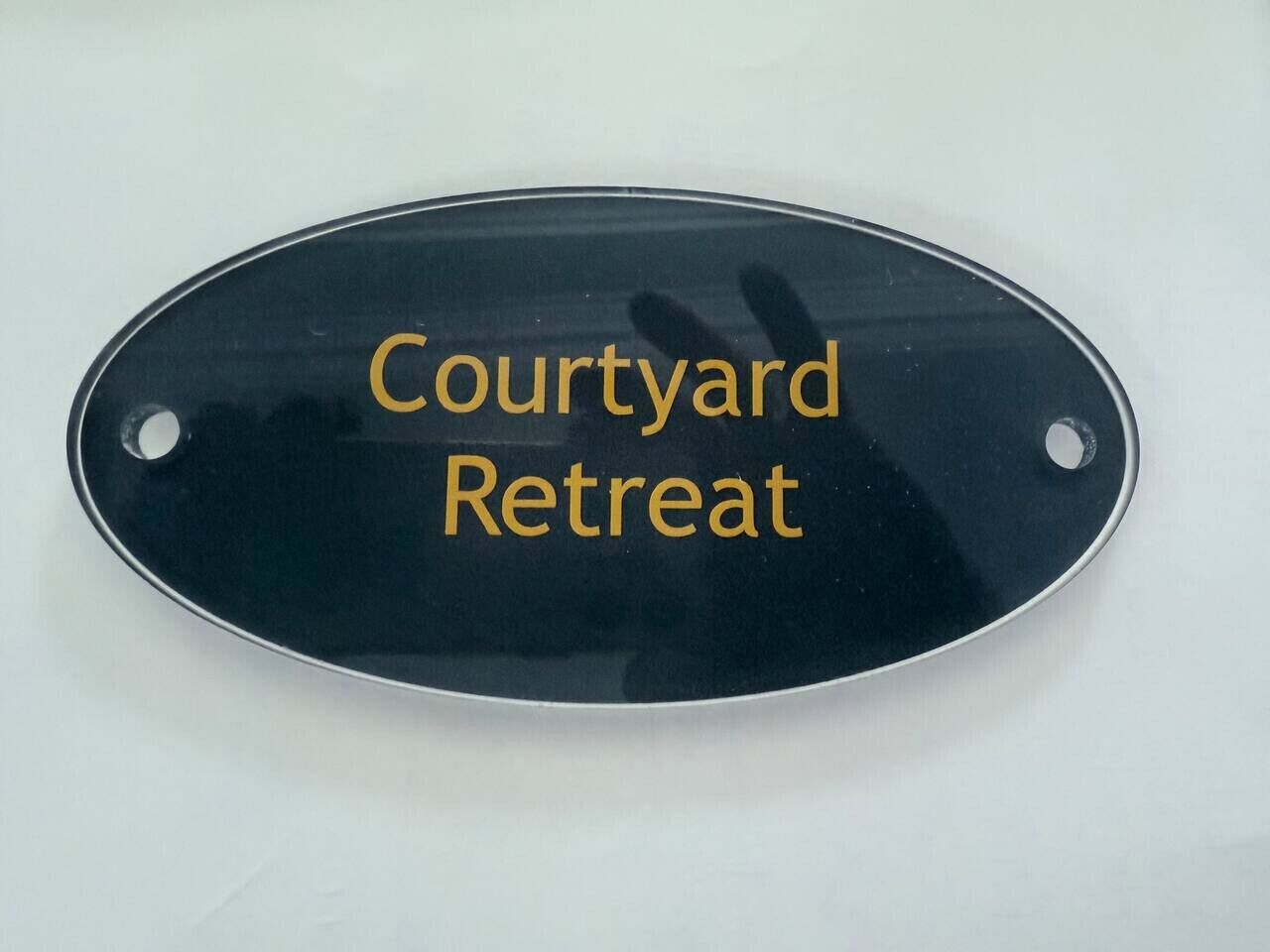 A black oval sign with the text "Courtyard Retreat" in gold lettering.