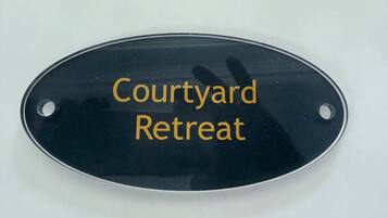 A black oval sign with the text "Courtyard Retreat" in gold lettering.