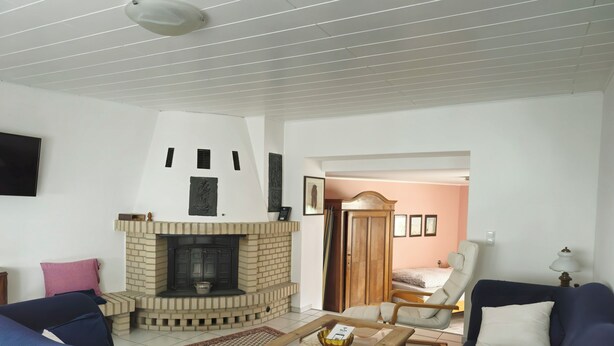 Ein Wohnzimmer mit Kamin aus Backstein, zwei Sofas, einem Couchtisch und einer Tür zu einem anderen Raum.
