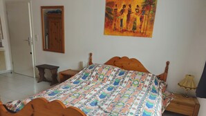 Ein Schlafzimmer mit einem hölzernen Bett, einem Nachttisch, einer Lampe, einem Spiegel und einem Bild an der Wand.