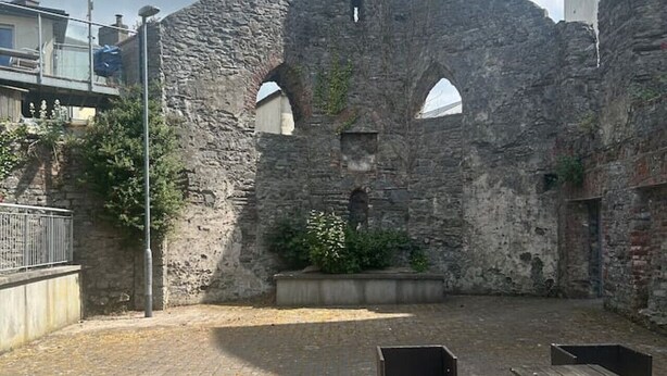 An outdoor courtyard with stone walls, a paved area, and wooden benches. - The Courtyard View Sligo! (Sligo)