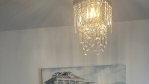 A room with a white wall, a white radiator, and a chandelier. - The Courtyard View Sligo! (Sligo)