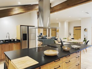 A modern kitchen with a central island, wooden cabinets, and a built-in stove.