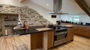 Uma cozinha moderna com parede de pedra, armários de madeira e uma ilha central.