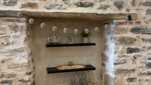 Lareira de pedra com prateleiras, uma vela e um vaso com flores secas.