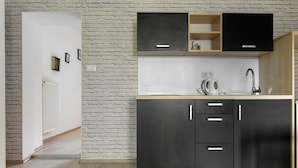 A modern kitchen with dark cabinets, a wooden countertop, and a built-in oven. - Euro Square Studios (Zagreb)