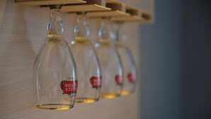 A row of empty wine glasses hanging from a wooden shelf. - Euro Square Studios (Zagreb)