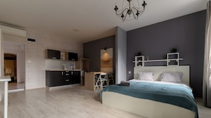 A modern bedroom with a large bed, a desk, and a kitchenette. - Euro Square Studios (Zagreb)