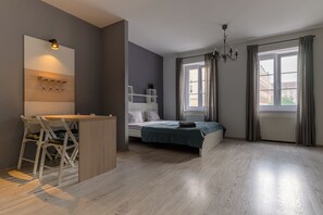 A modern bedroom with a bed, a desk with chairs, a chandelier, and a large window with curtains. - Euro Square Studios (Zagreb)