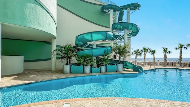 Una piscina con una estructura de tobogán acuático de varios niveles a su lado.