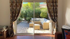A room with a sliding glass door leading to an outdoor patio with a sofa and a table. - Renovated Provencal villa 50 m from the sea Résidence Hélios (Saint Raphael)