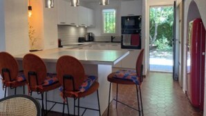 A modern kitchen with a central island, pendant lighting, and a dining area with chairs. - Renovated Provencal villa 50 m from the sea Résidence Hélios (Saint Raphael)