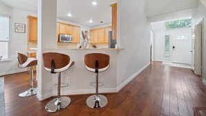 A modern kitchen with wooden cabinets, stainless steel appliances, and two bar stools. - Serenity of Spring, TX & The Woodlands - Modern 4BR Furnished Home (Spring)