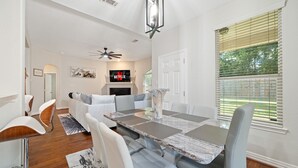 A dining area with a marble table, white chairs, and a ceiling fan. - Serenity of Spring, TX & The Woodlands - Modern 4BR Furnished Home (Spring)