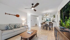 A modern living room with a sofa, coffee table, and a dining area with chairs and a table.