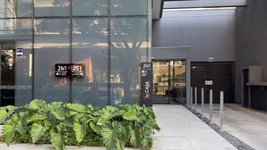 A modern building with large glass windows reflecting the surroundings. There are signs indicating the building's address and a logo for 'CASA'. - La Casa Brooklin (São Paulo)