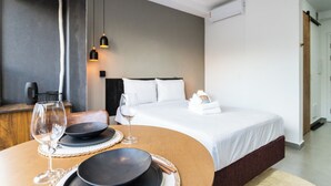 A hotel room with a bed, bedside table, and a dining area with a table set for two. - La Casa Brooklin (São Paulo)