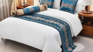 A neatly made bed with a blue and white bedspread, a matching throw blanket, and decorative pillows. - Hotel Kelson Dx  (New Delhi)
