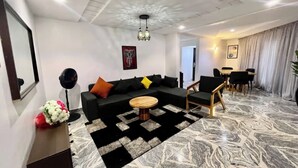 Un salon moderne avec un canapé d’angle, une table basse ronde et un coin repas comprenant une table et des chaises.