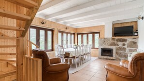 A wooden interior with a fireplace, dining table, and leather chairs.