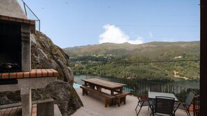 A patio with a table and benches overlooking a river and mountains.