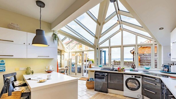 A spacious kitchen with a large island, built-in appliances, and a skylight. - Harbour View House | Old Town, Sea Views | Sleeps 8 (North Yorkshire)