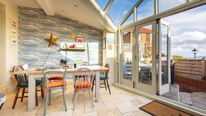 A dining area with a high ceiling, patterned wall, and a view of the outside. - Harbour View House | Old Town, Sea Views | Sleeps 8 (North Yorkshire)