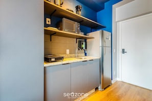 Una cocina compacta con armarios grises, microondas, cafetera y refrigerador.