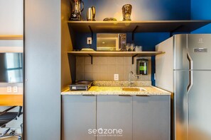 A compact kitchen with a microwave, toaster, and refrigerator. - Modern and Fully Equipped Accommodations Near the Metro and Praca da Republica - Dnrs (São Paulo)
