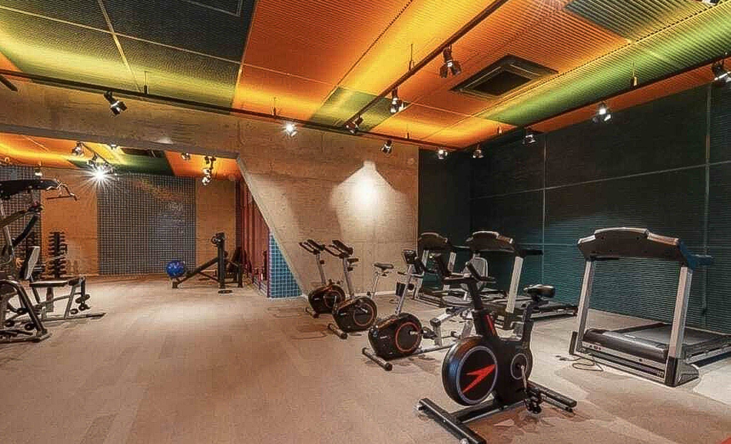 Uma academia com diversos equipamentos de exercício, incluindo esteiras, bicicletas ergométricas e aparelhos de musculação.