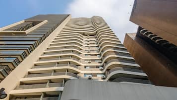 A high-rise hotel with multiple balconies, a modern architectural design, and a clear sky in the background.