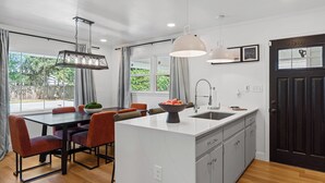 A modern kitchen with a central island, pendant lights, and a view of the outdoors.