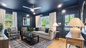 A modern living room with a dark blue wall, a ceiling fan, a sofa, a coffee table, and a lamp.