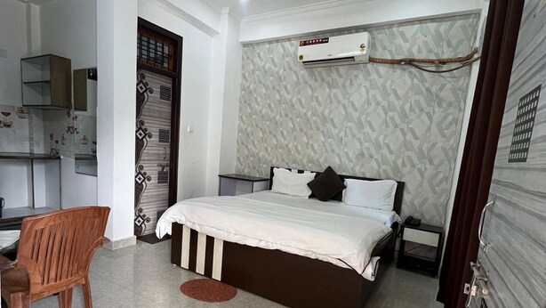 A bedroom with a bed, a desk, a chair, a ceiling fan, and an air conditioning unit. - Staylo Masterprice Inn (Lucknow)