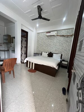 Une chambre à coucher comprenant un lit, un bureau, une chaise, un ventilateur de plafond et un appareil de climatisation.