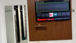 A television mounted on a wooden panel wall with a control panel below it. - Staylo Masterprice Inn (Lucknow)