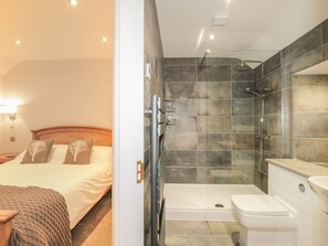 Una habitación de hotel con cama, mesita de noche y baño completo con ducha, bañera y retrete.