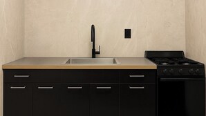 A modern kitchen with a black countertop, a stainless steel sink, and a black stove. - 3 KING Beds & Free parking • Central Place (Pittsburgh)